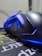 A close-up view of a sleek, black gaming mouse with blue LED lighting accents. The mouse is resting on a mouse pad with Asian characters and yellow and white text. The focus is on the curves and lighting of the mouse, giving it a futuristic and stylish appearance.
