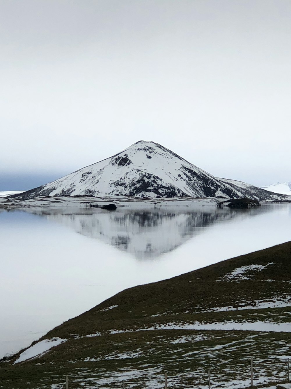 una montaña cubierta de nieve sentada junto a un lago