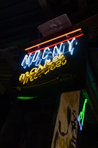 A dark, glitchy close-up of an electric blue neon sign flickering against black metal textures