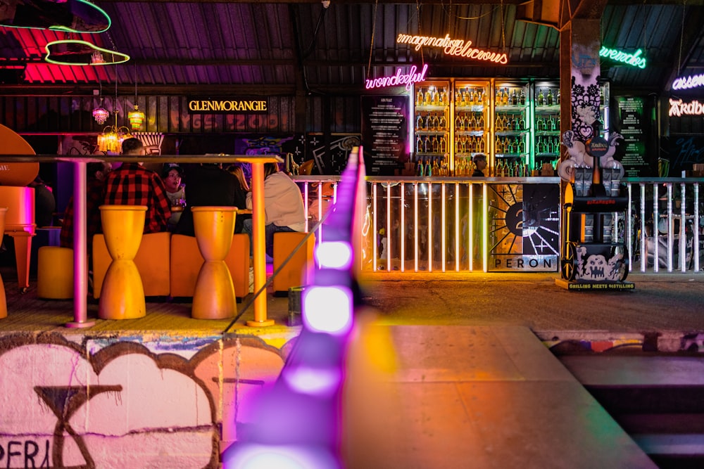 a group of people sitting at a bar with neon lights