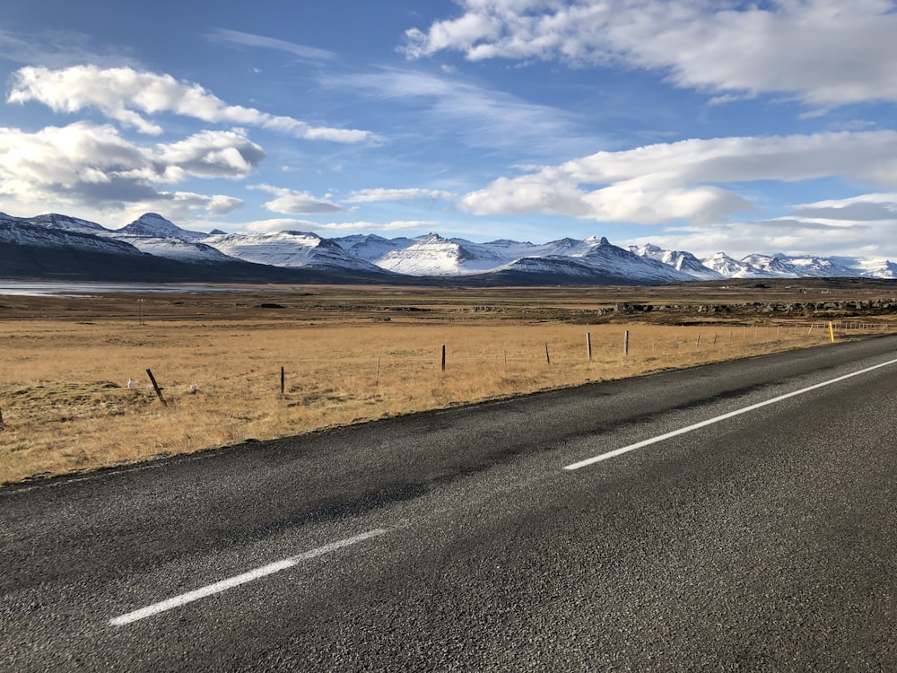 an empty road with mountains in the background