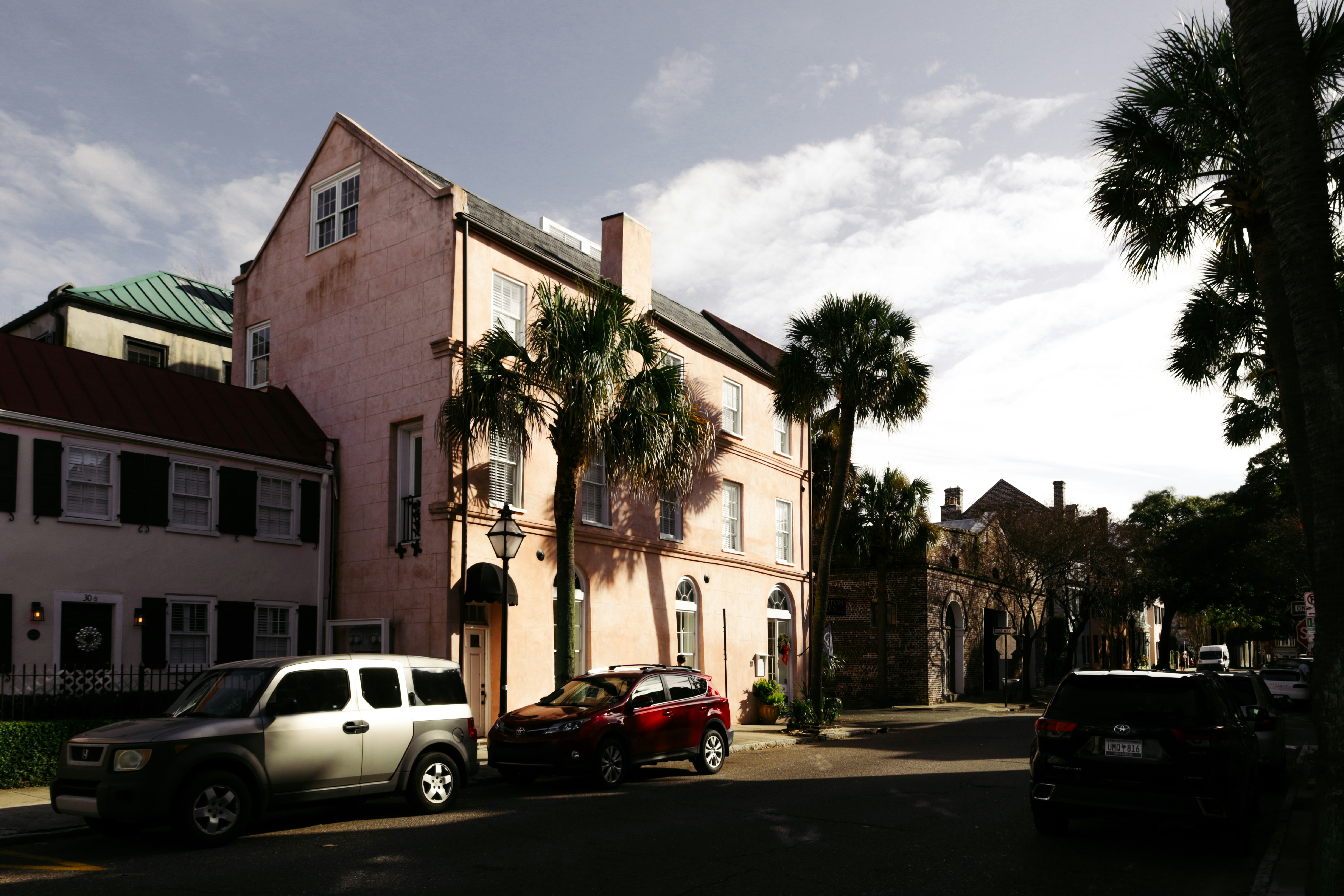 a couple of cars parked in front of a pink building