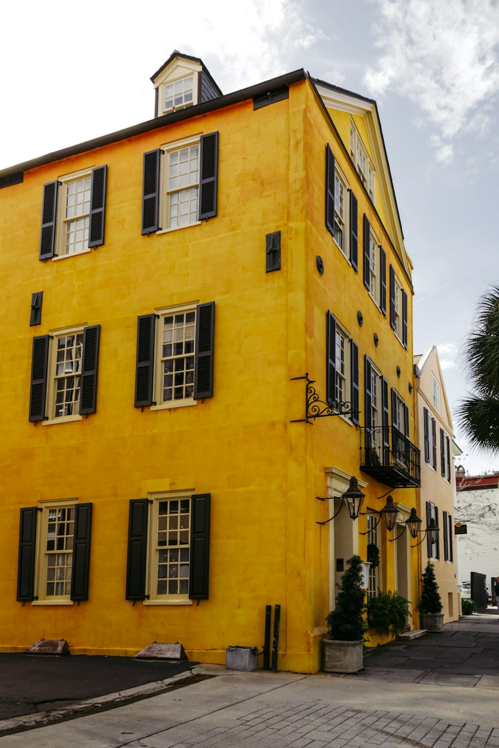 a yellow building with black shutters and a clock tower