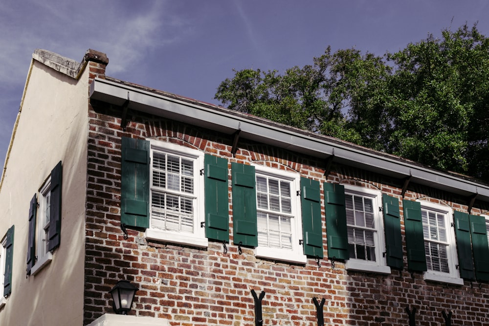 a brick building with green shutters and white windows