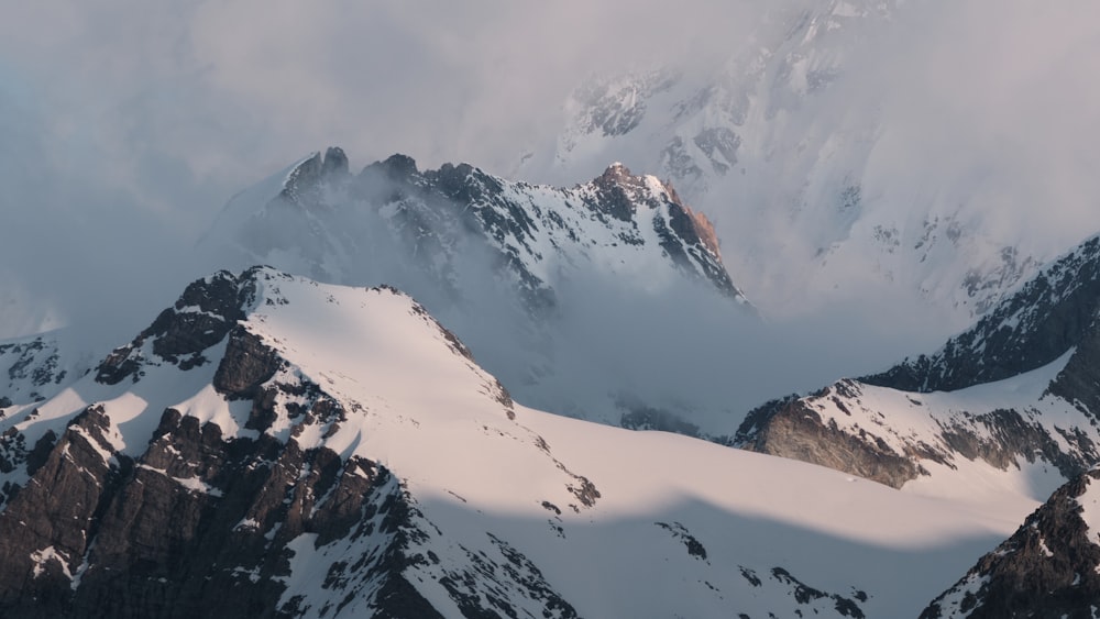 a mountain range covered in snow under a cloudy sky