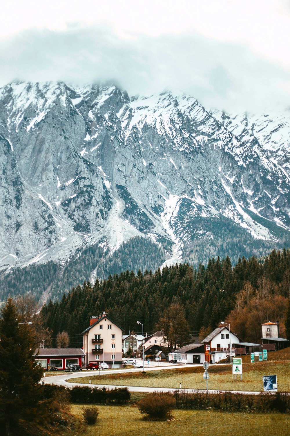 a snowy mountain range with houses and trees in the foreground