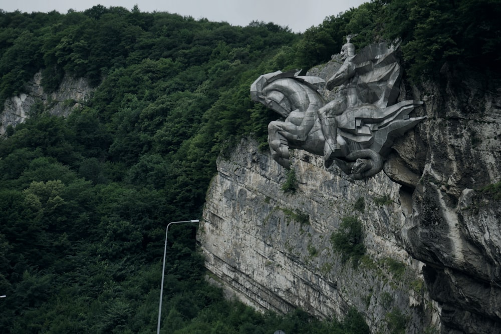 a statue of a dragon on the side of a cliff