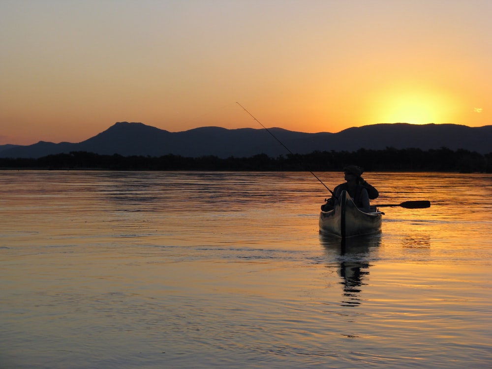 a person in a kayak on a lake at sunset