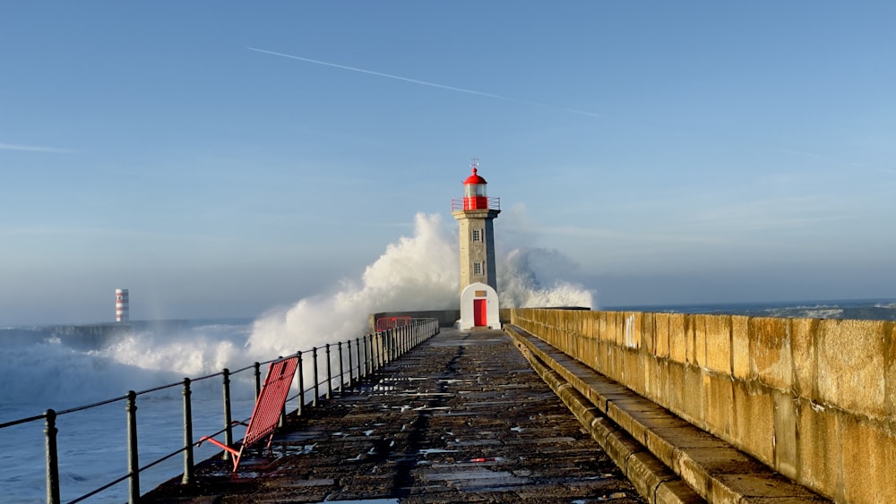 a lighthouse on a pier with waves crashing in the background