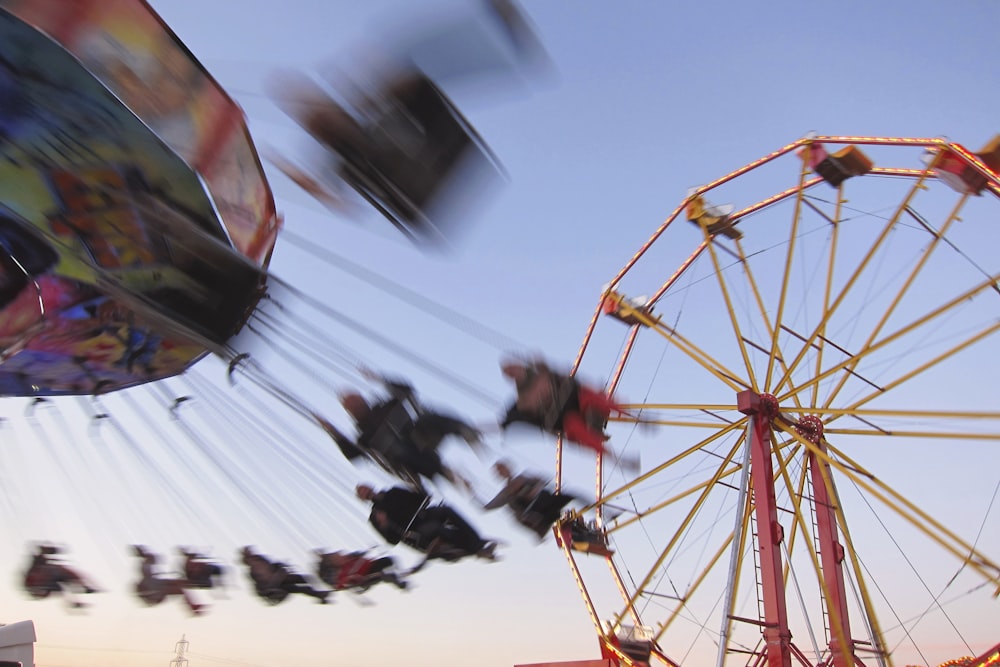 a carnival ride with people on it and a ferris wheel in the background