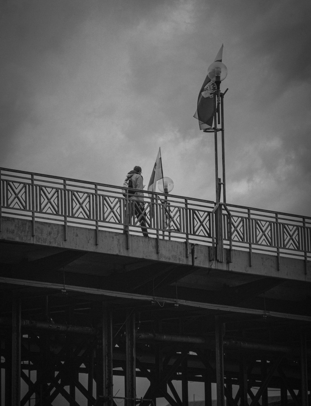 a man walking across a bridge with a kite