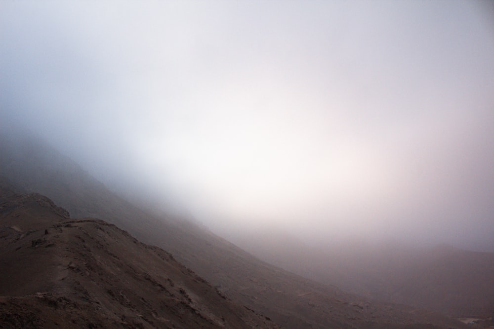 a mountain covered in fog and clouds on a cloudy day