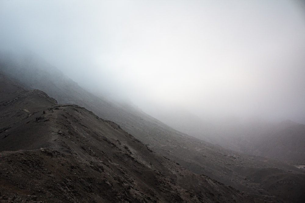 a very tall mountain covered in fog on a cloudy day