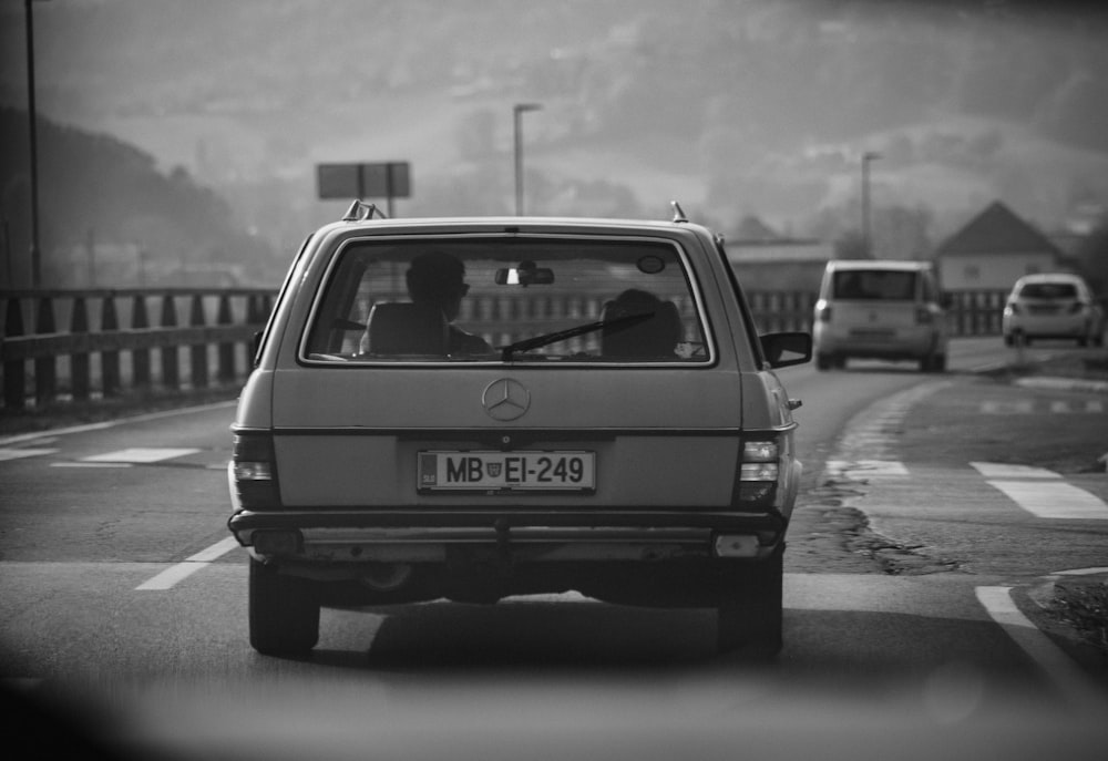 a black and white photo of a car driving down the road