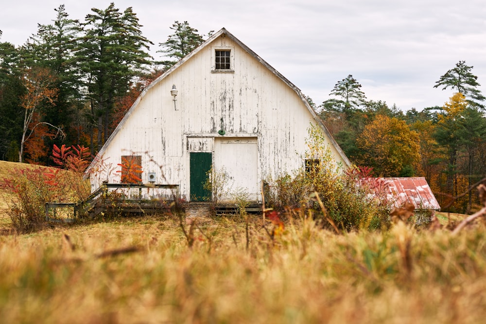 a white barn with a green door in a field