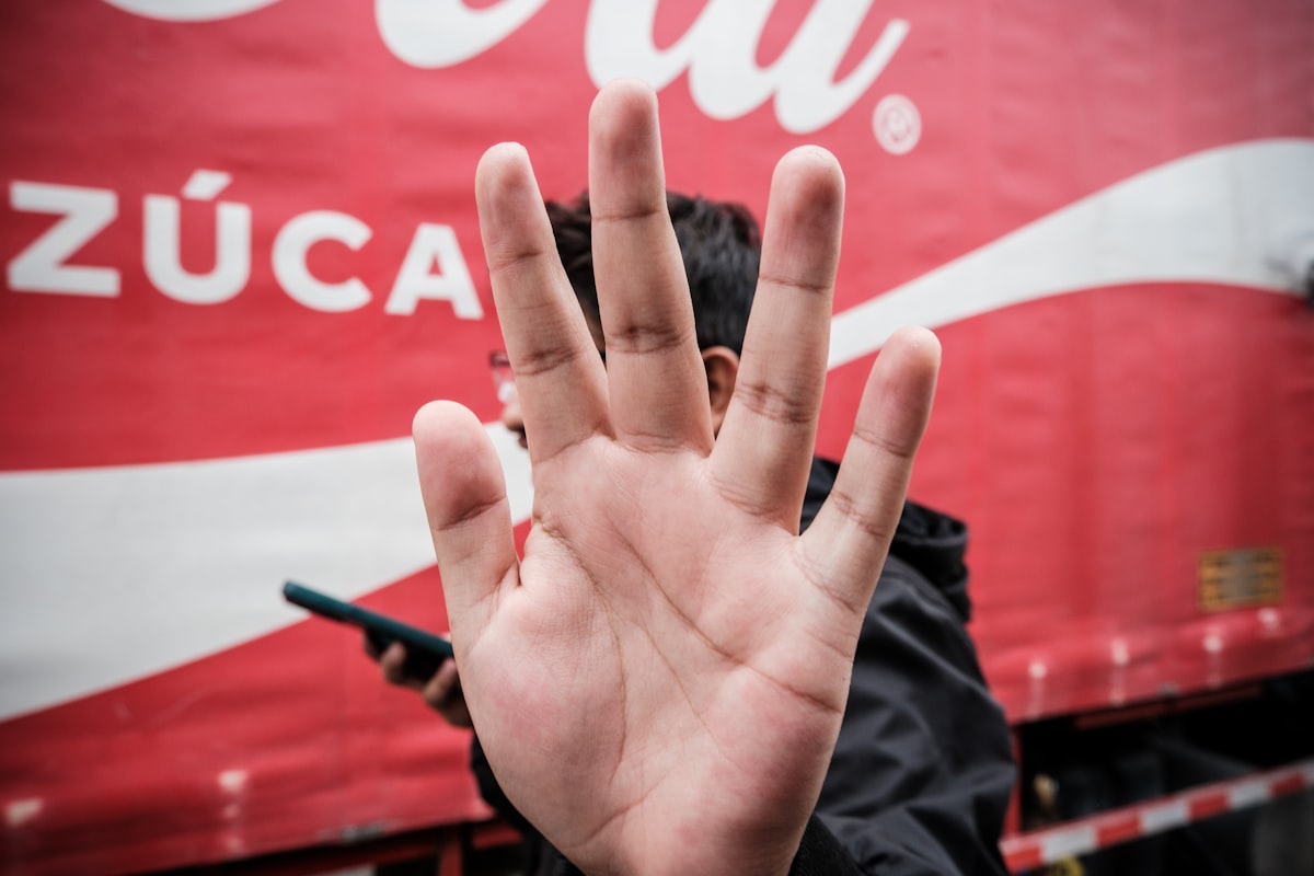 a person with their hand up in front of a coca - cola truck