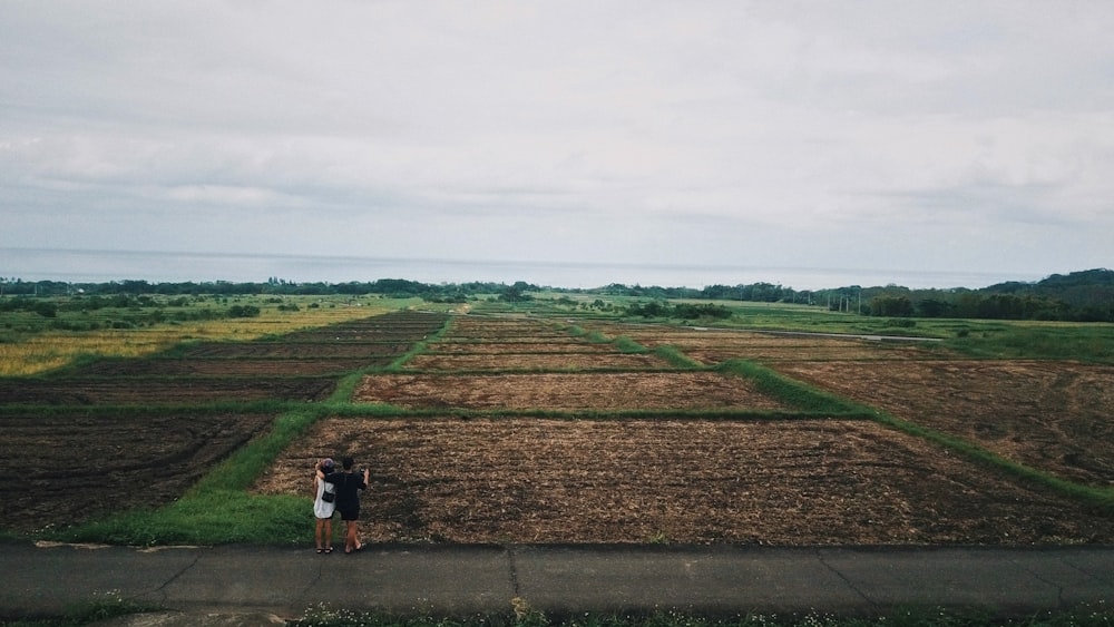 a person standing on a sidewalk in front of a field