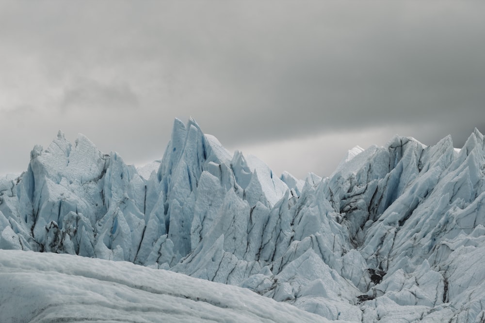 a very tall mountain covered in snow under a cloudy sky