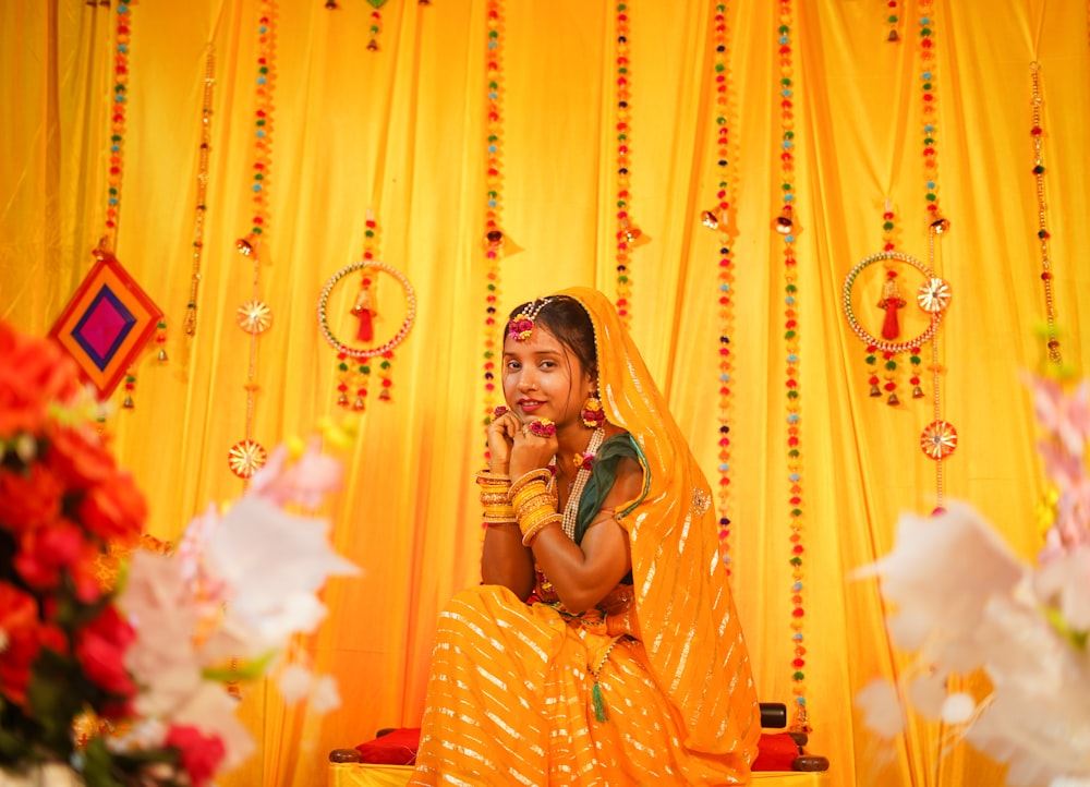 a woman in a yellow sari sitting on a bench