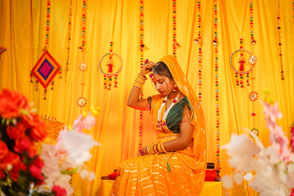 a woman in a yellow sari sitting on a chair