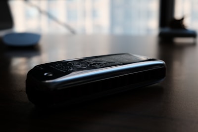 Close-up of a harmonica resting on an old wooden table.