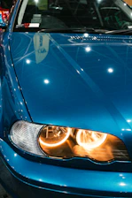 Close-up of a shiny blue car with yellow highlights under bright showroom lights.