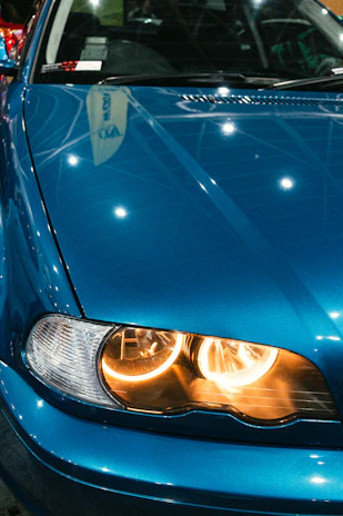 Close-up of a shiny blue car with yellow highlights under bright showroom lights.