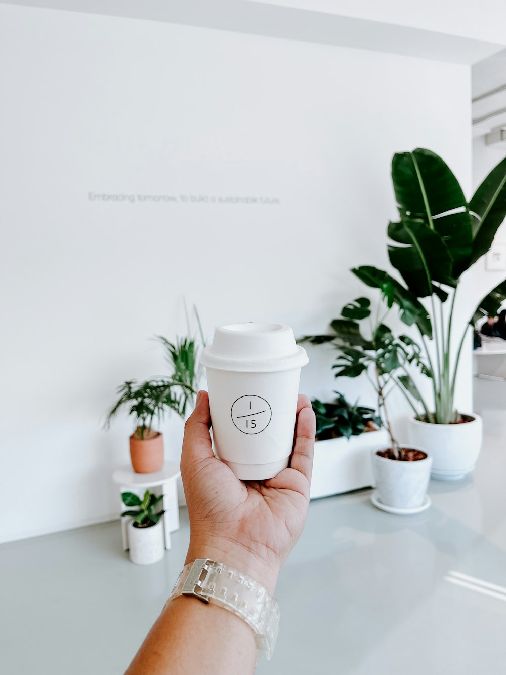 a hand holding a coffee cup with a smiley face drawn on it