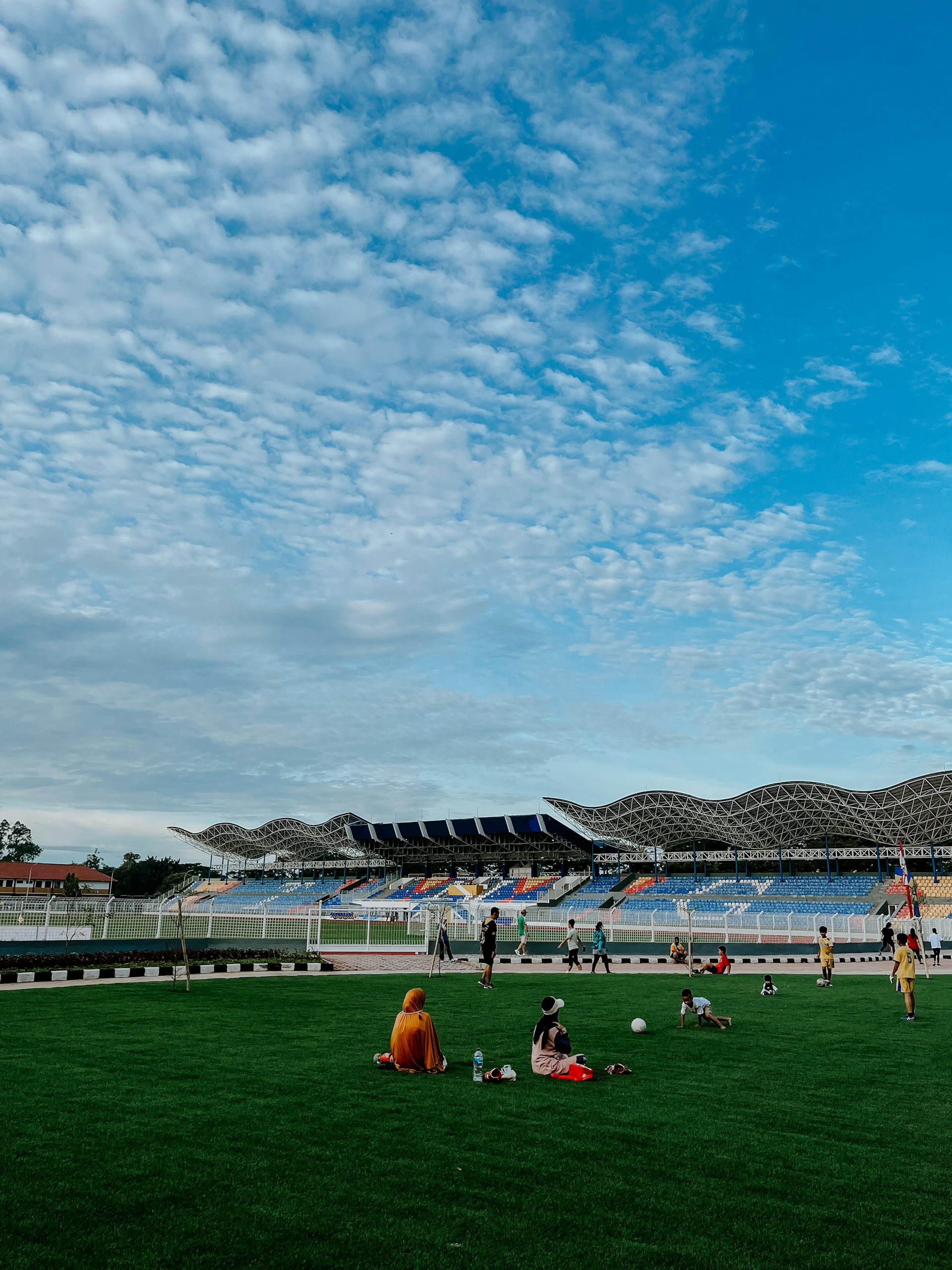 The fully renovated stadium gleaming under bright sunlight, with modern seating, lush green field, and vibrant atmosphere.