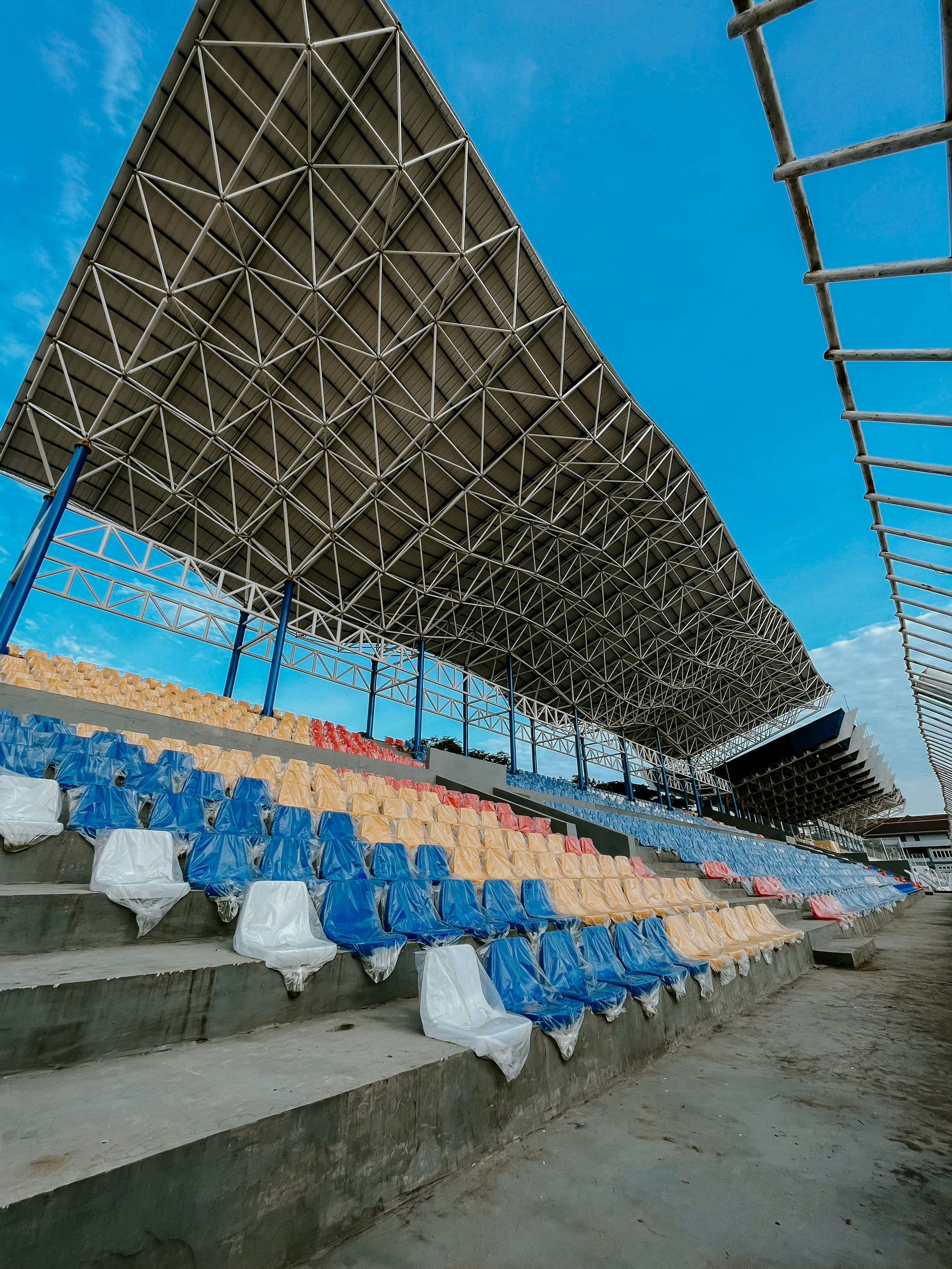 Large stadium canopy covering seating sections with tensile fabric roof structure at sports venue