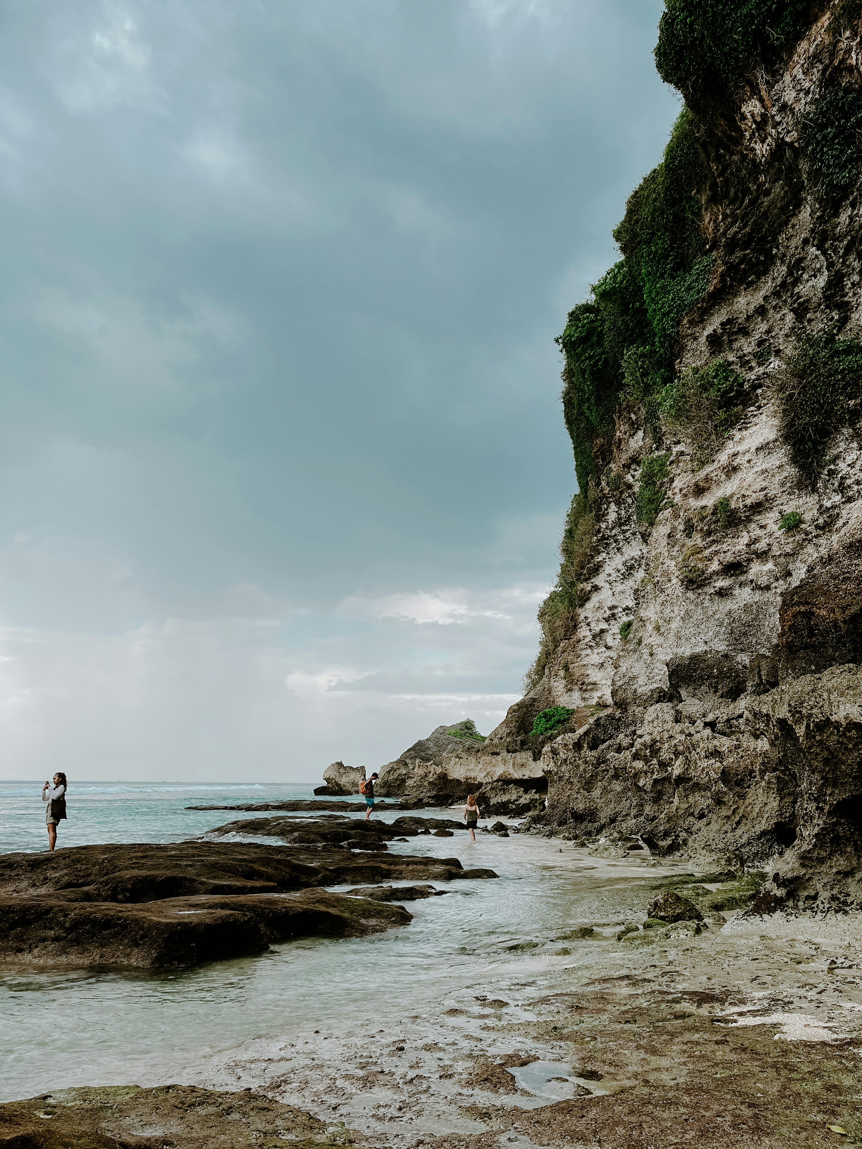 a man standing on a rocky beach next to the ocean