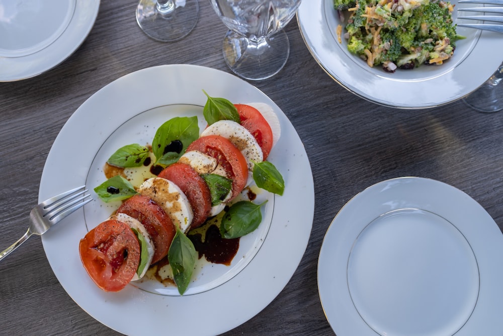 a white plate topped with sliced tomatoes and veggies