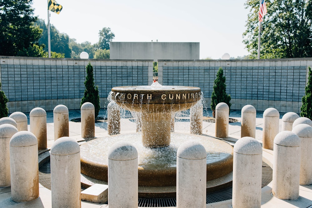 a fountain surrounded by white pillars and trees