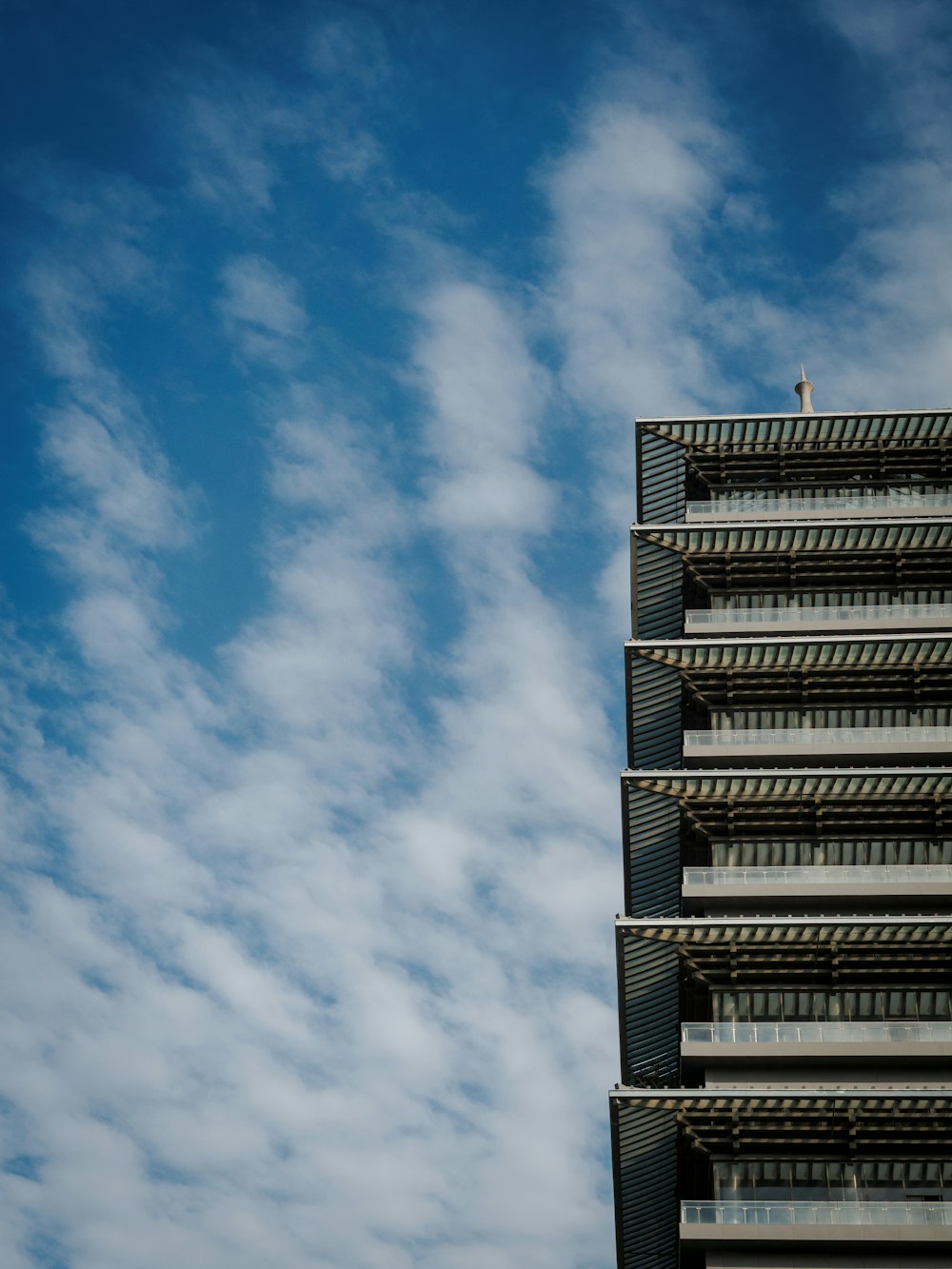 Ein hohes Gebäude unter einem wolkenverhangenen blauen Himmel