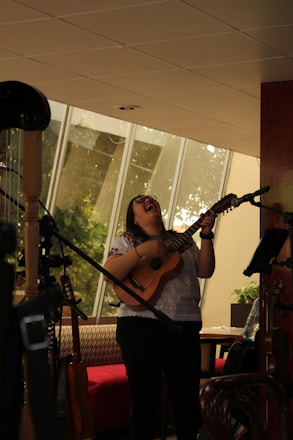A person joyfully playing cavaquinho in a cozy home setting with samba music notes floating around.