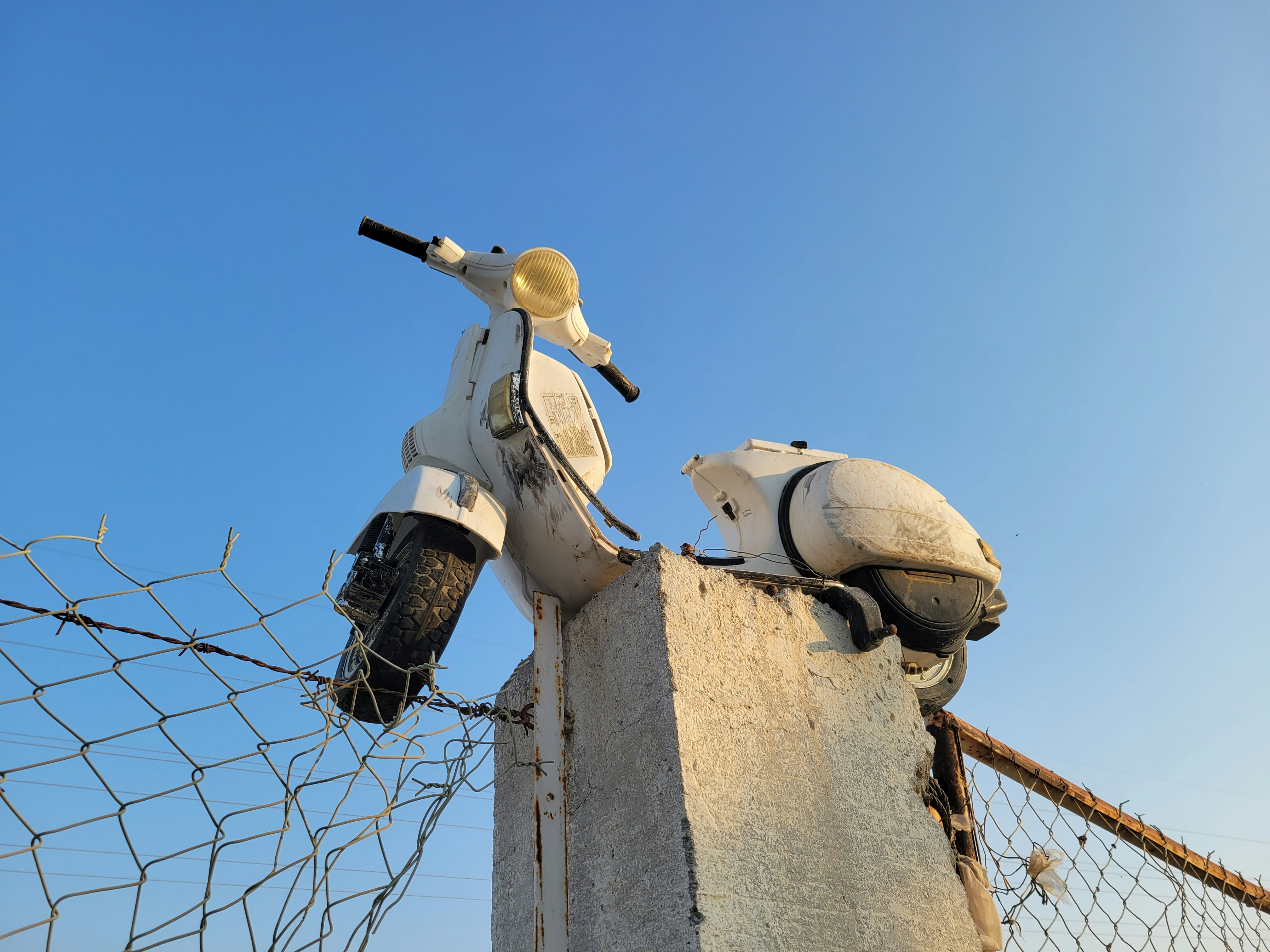 a scooter is parked next to a barbed wire fence