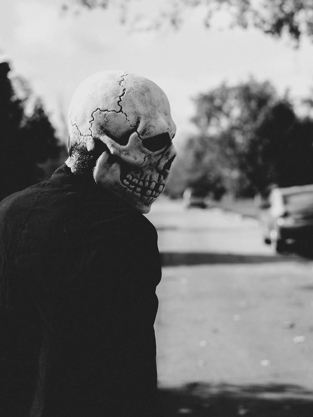a man with a skull on his head walking down the street