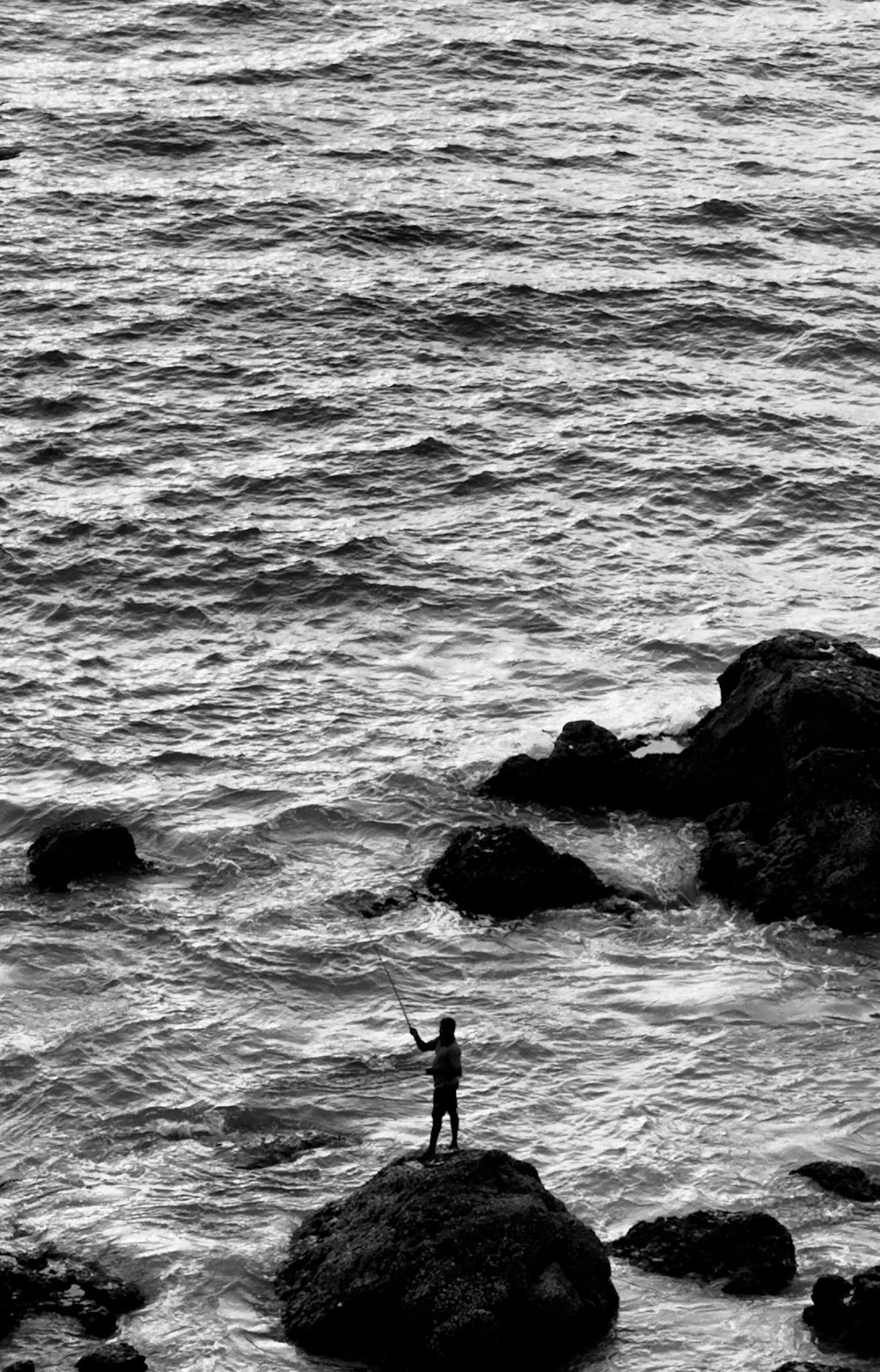 una persona in piedi su una roccia nell'oceano