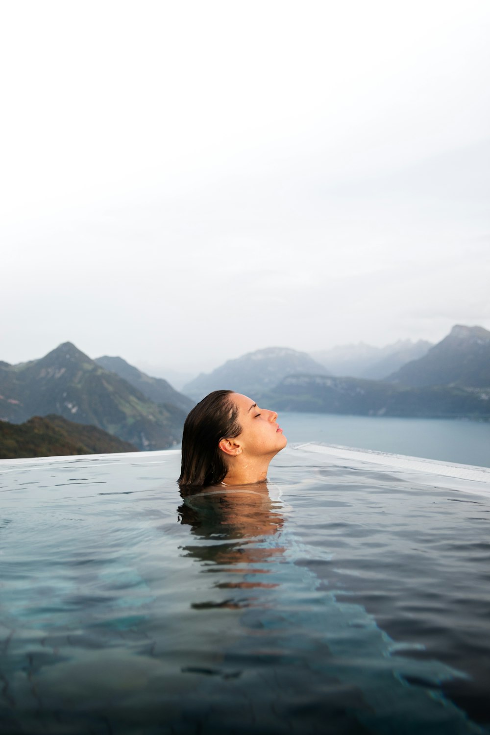 a woman floating in a pool of water with mountains in the background