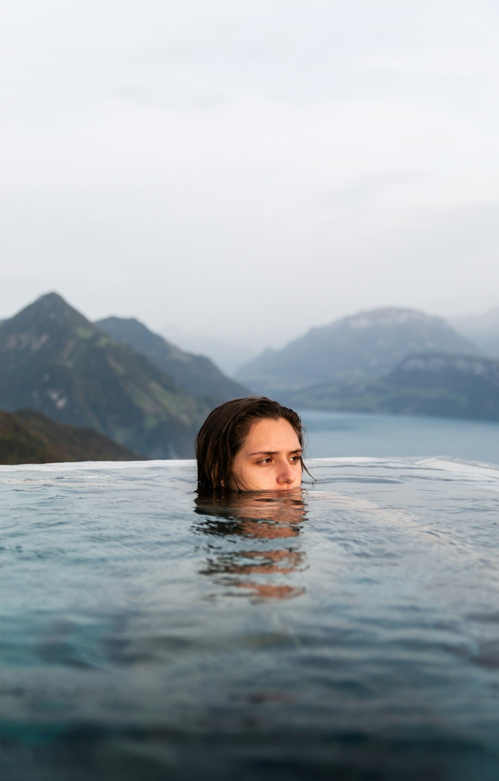 a woman swimming in a pool with mountains in the background
