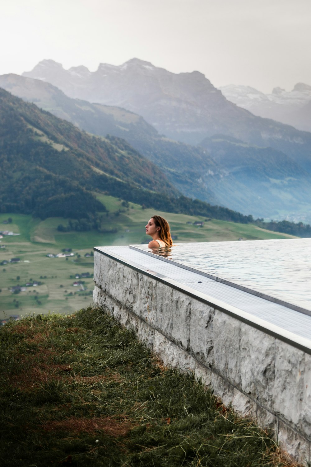 a woman sitting on top of a stone wall next to a body of water