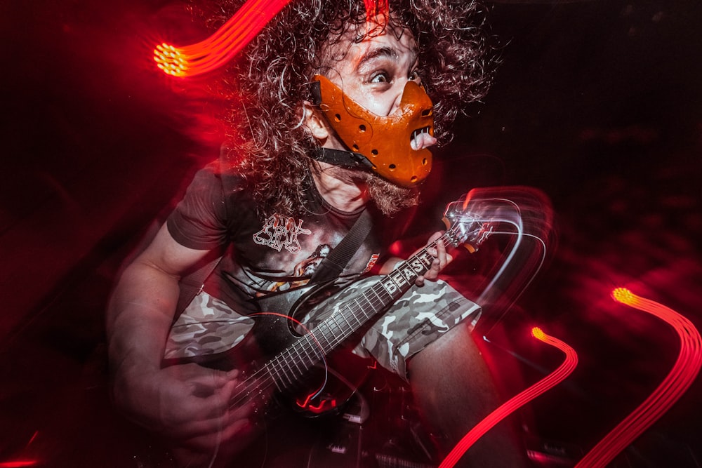 a man with a mask playing a guitar