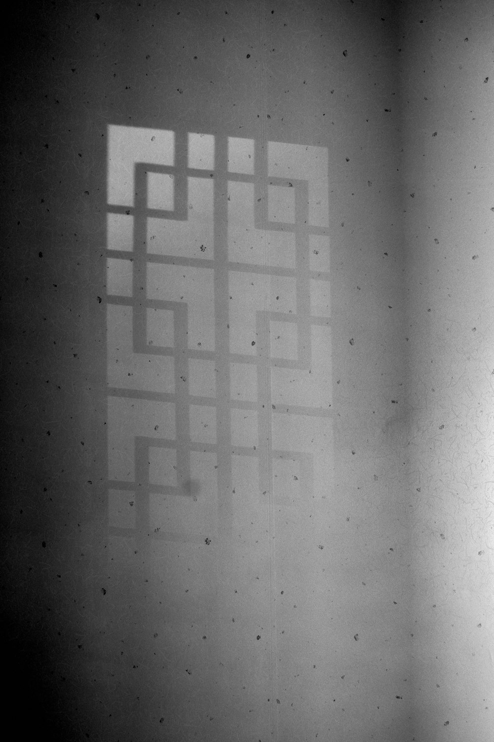 a black and white photo of a wall with a shadow on it