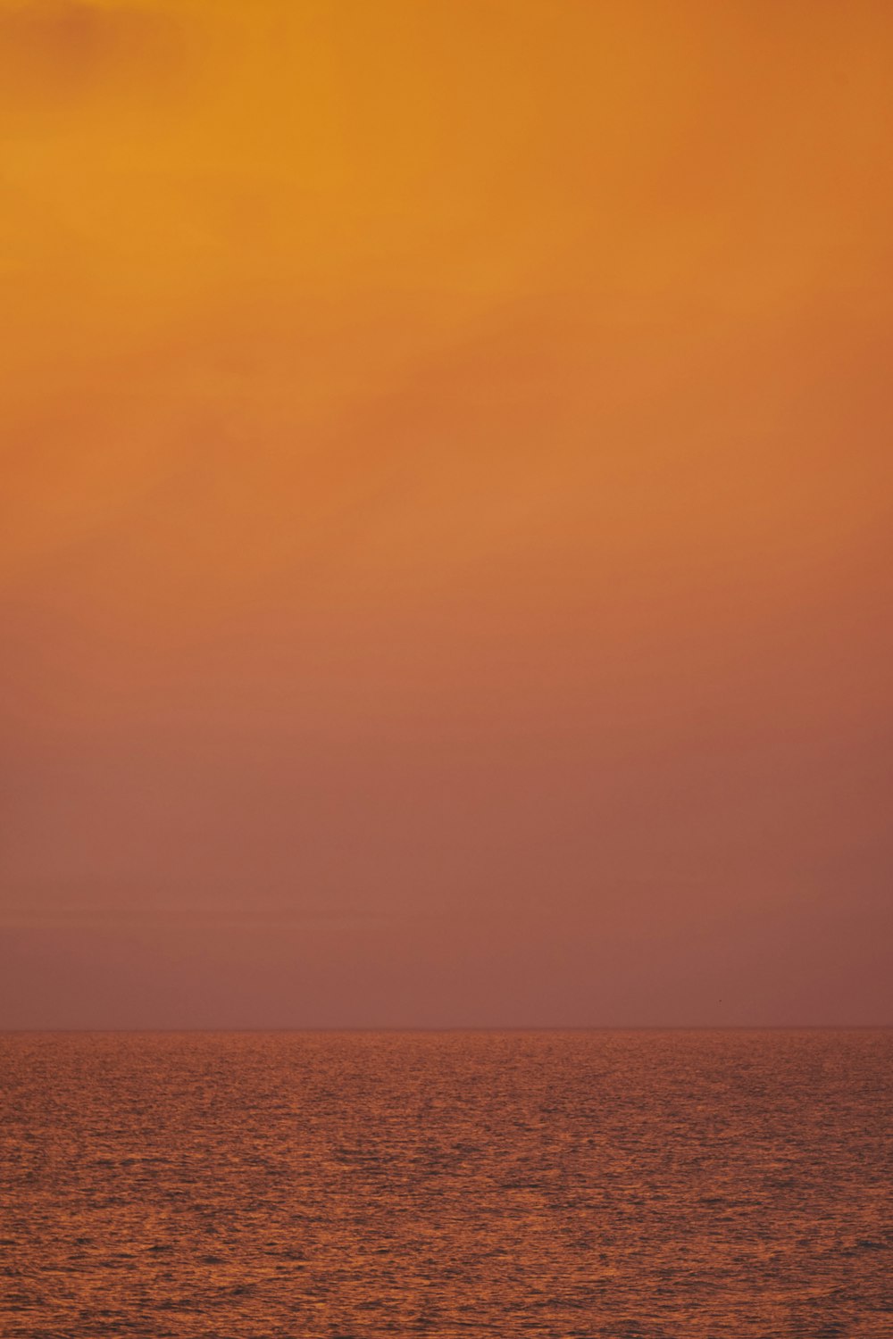 an orange sky over the ocean at sunset