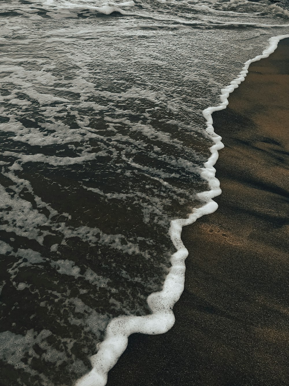 a black and white photo of a wave coming in to the shore