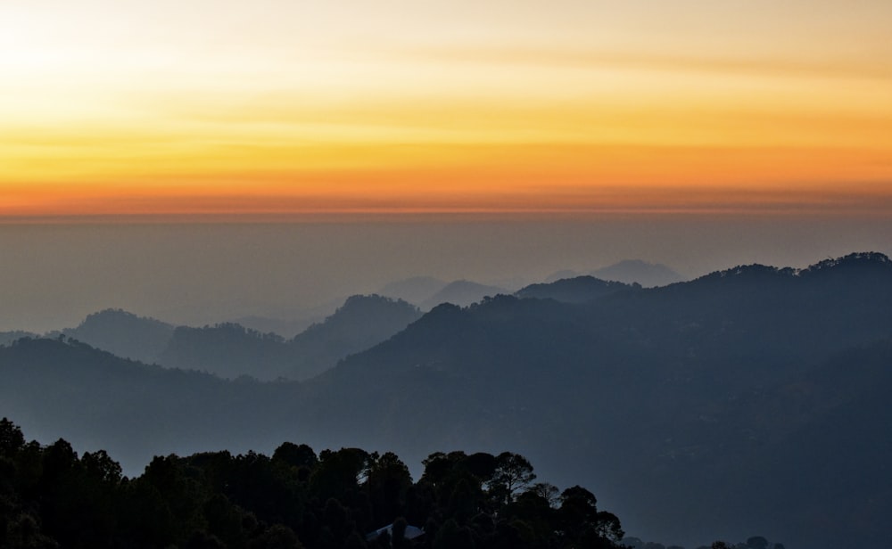 the sun is setting over a mountain range