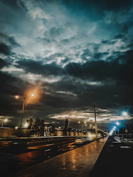 A moody photograph of a city street glowing with warm streetlights as twilight fades.