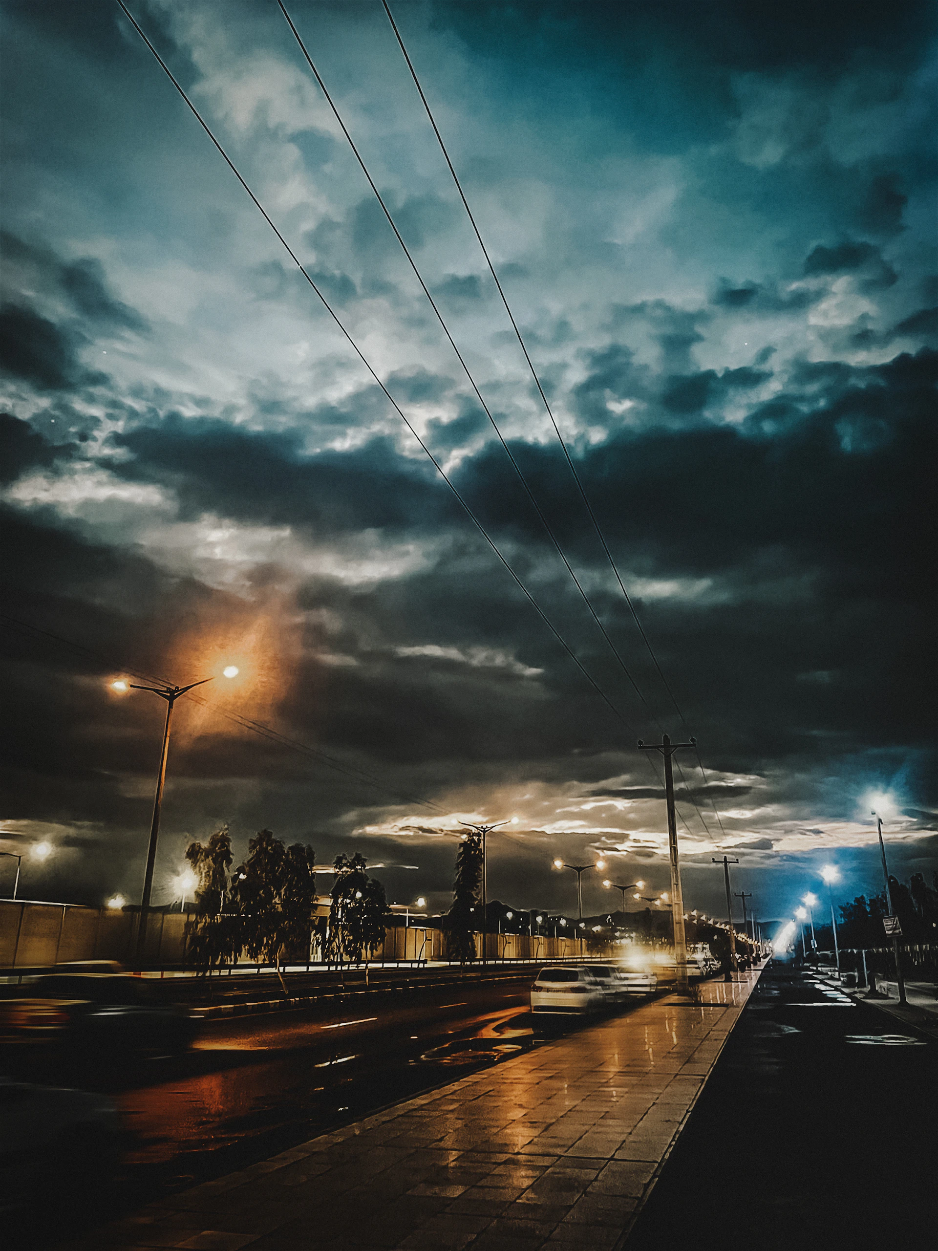A cinematic still capturing a moody urban landscape at dusk, with deep shadows and warm streetlights reflecting off wet pavement.