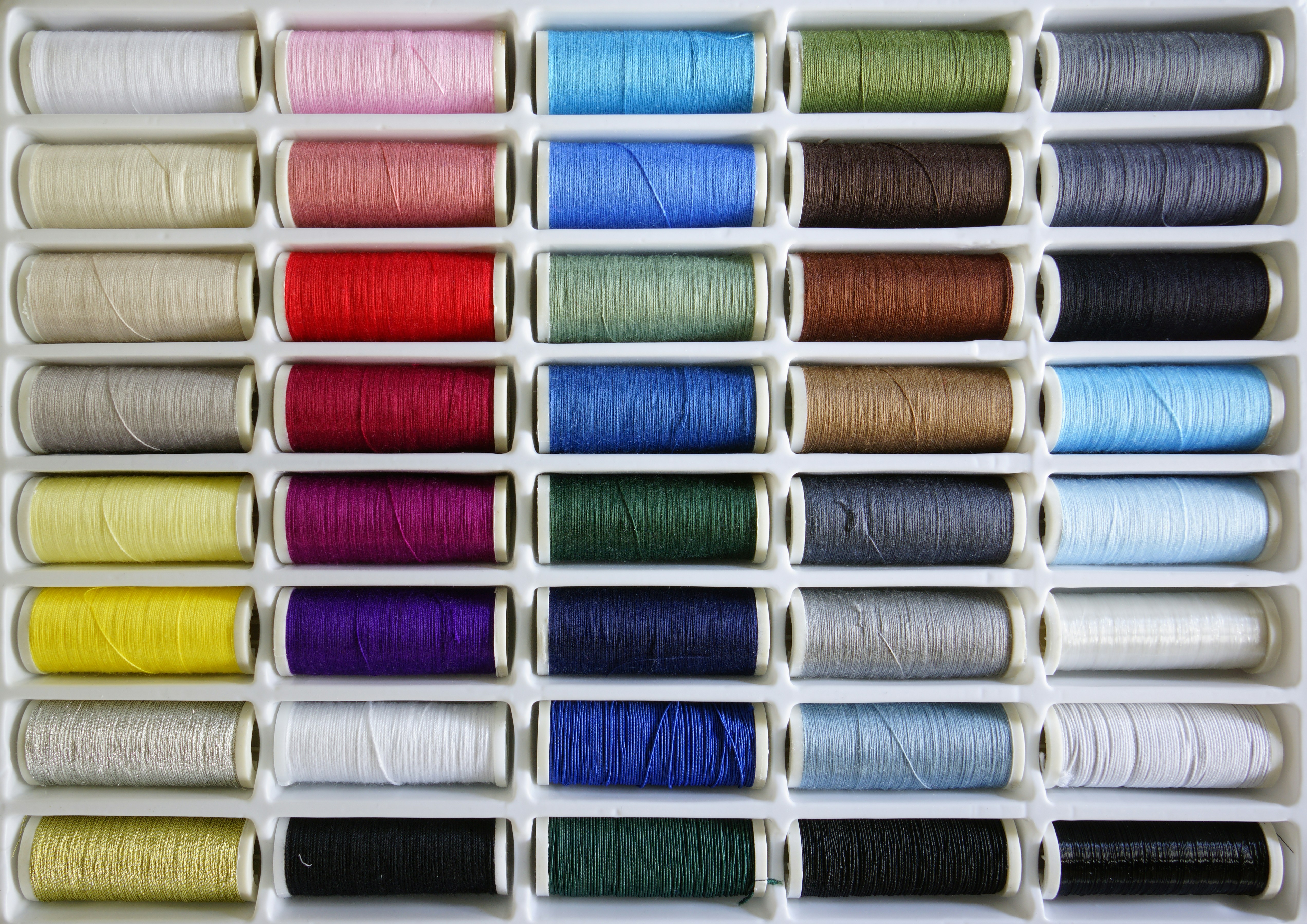 A rack of spools of thread and spools of thread photo – Free Linen ...