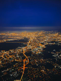 A sleek, glowing aerial view of a futuristic Indonesian city at night, with digital overlays highlighting smart infrastructure.